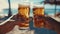 Close up of two men hands holding cold craft beer glasses at summer beach cafe
