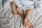 Close-up of two pairs of toddler girls feet on the bed under the blanket. Light blue and beige tones