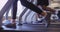 Close up of two people feet running on treadmill in gym low angle view