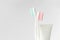 Close up of two plastic white toothbrushes with pink and blue bristle and toothpaste in tube on white background.