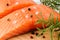 Close-up of two raw chilled salmon fillets with pepper grains, salt and fresh rosemary on a brown wood cutting board. Healthy