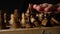 Close up of two rows of black chess pieces on chessboard. Woman\'s hand toppling wooden figures on chessboard on black