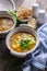 Close-up two servings of chicken soup with croutons, vegetables, fresh parsley in a white bowl on a wooden table. Vertical shot