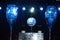 Close up of two water filled wine glasses and a beautiful glass globe with vivid blue back lights at a nigh time outdoor event,