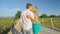 CLOSE UP: Two young sweethearts kiss while holding hands and crossing a bridge