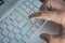 Close-up of typing male hands, grey silver keyboard button close up. Finger presses the enter button