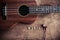 Close up of ukulele and earphone on old wood background