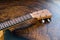 Close-up of a ukulele fretboard - small light brown instrument on beautiful wooden table