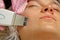 Close-up. Ultrasonic face cleaning. Modern equipment. Beautician does cosmetic procedure on woman face
