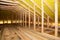 A close-up on an unfinished attic construction with wooden roof beams, planks, rafters, ceiling joists and vapor barrier film