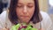 Close-up of Unhappy overweight woman sitting at a table and looking at a bowl of salad