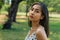 Close-up of unhappy Southeast Asian woman with tears looking at camera in outdoor park. Portrait of depressed and