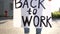 Close-up of an unidentifiable woman holding a poster at her feet with the inscription Back to work. Mass protests