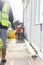 A close up of a unknown builder wearing a high visibility vest and holding a hard hat. Builder, safety, building site, laborer