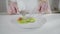 Close-up of unknown girl cutting cucumber slices with knife and fork and eating fresh organic salad. Young Caucasian