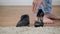 Close-up of unrecognizable barefoot Caucasian man`s feet walking at the background and taking women`s high heel shoe