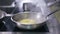 Close-up unrecognizable cook pouring water in pan frying pineapple in slow motion. Male Caucasian hand in glove adding