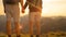 CLOSE UP: Unrecognizable couple holding hands while hiking up to mountaintop.