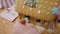 Close-up unrecognizable girl placing snowman candy on gingerbread house. Little Caucasian child cooking delicious tasty