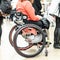 Close up of unrecognizable hanicapped woman on a wheelchair queuing in line to perform everyday tasks.