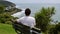 CLOSE UP: Unrecognizable man sitting on bench looks at the spectacular seaside.