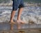 Close up of an unrecognizable man wading in the foaming waves of a beach