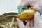 Close-up of unrecognizable man wearing peeling potato with peeler knife over metal bowl full of peelings. Composting.