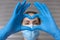 Close up of unrecognizable nurse with medical mask and protective gloves. She is forming a heart with her hands. Health concept