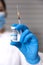 Close up of unrecognizable nurse with medical mask and protective gloves showing a syringe and a glass vial with Covid-19 vaccine