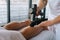 Close-up of unrecognizable professional male masseur massaging leg calf muscles using massage gun percussion tool of