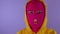 Close up of unrecognizable woman in pink balaclava shows her tongue on purple background. Unknown female in mask sticks