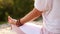 Close-up of unrecognizable woman sitting in lotus pose outdoors, back view, tracking shot.