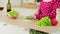 Close-up of an unrecognizable woman is slicing a cucumber for a salad, standing in a modern kitchen. Vitamins, dietary