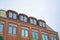 Close up of upper exterior of a building with red brick wall and attic windows