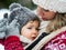 Close-up of upset small daughter in carrier and mother in winter nature.