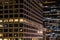 Close up urban scene of modern buildings at night with colorful glowing windows, lights and reflections