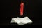 Close up of a used female sanitary towel tampax that is deposited on white original paper on a black background