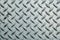 Close up of used rough steel sheet with diamond plate pattern/metallic texture background