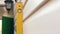 Close-up using a yellow level tool, a builder measures the plane of a wall in a house under construction. Suburban construction an