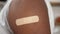 Close up vaccinated African American man with medical plaster on shoulder