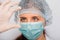 Close-up of a vaccine ampoule in the hands of a woman doctor. Lab technician in a white coat, medical hat, mask and gloves, holds