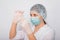 Close-up of a vaccine ampoule in the hands of a woman doctor. Lab technician in a white coat, medical hat, mask and gloves, holds