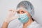 Close-up of a vaccine ampoule in the hands of a woman doctor. Lab technician in a white coat, medical hat, mask and gloves, holds