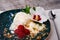 Close-up of vanilla ice cream with raspberries. A blue bowl with ice cream and a flower on a fabric. Sweet desserts for gourmets.