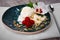 Close-up of vanilla ice cream with raspberries. Blue bowl with ice cream, mint and nuts on a table. Sweet and cold summer snacks.