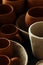 A close-up of various drying clay tableware on a shelf. A pottery studio concept. Craftmade dishes, bowls, pots, mugs of