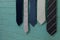 Close up of various neckties hanging by green wall