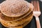 Close-up of vegan banana pancakes stack on black plate with copper fork