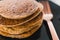 Close-up of vegan banana pancakes stack on black plate with copper fork