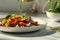 Close-up of vegetable salad with olive oil pouring.